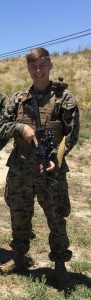 Bill Davis in a camouflaged uniform standing outside.