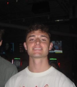 George Vondriska in a white t-shirt smiling at the camera.
