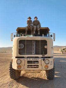 Zoe Atkins sitting on the top of a military truck with another person in uniform.