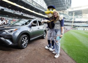 Abygail Boyle standing next to a car with Bernie Brewer, mascot for the Milwaukee Brewers.
