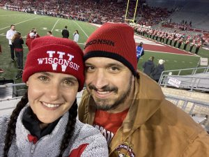Brian Bieniek and a woman wearing red hats at a Badgers football game.