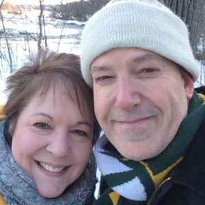 Dale Mohr wearing a hat and a woman wearing a scarf smiling at the camera with snow in the background.