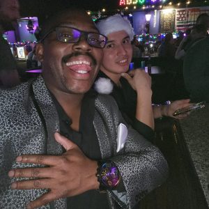 Gregory McClain and another individual in a Santa hat take a selfie at a bar.