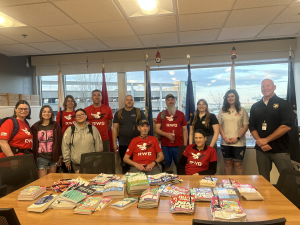 Community members and uw-madison students standing in front of a conference table filled with crossword puzzle books at the VA hospital.