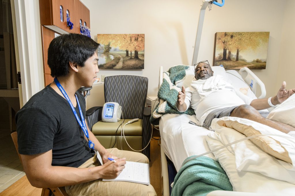 Alex Siy documenting a veteran's oral history in a hospital setting.