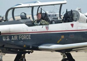 Dustin Lewis in uniform inside a fighter jet with "U.S. Air Force" on it.