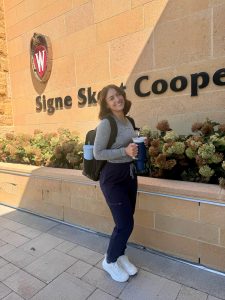 Mira Tcherneva standing in front of a UW-Madison building holding a water bottle and wearing a backpack.