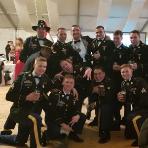 Zach Gerras in uniform at the Army Ball posing with a group of other soldiers.