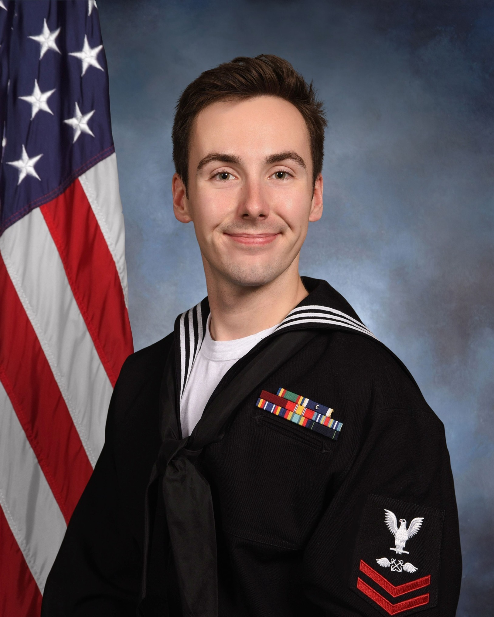 Jacob Warner in uniform sitting in front of a U.S. flag smiling for a photo.