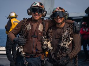 Frank Torres in uniform with another soldier outside by a body of water.