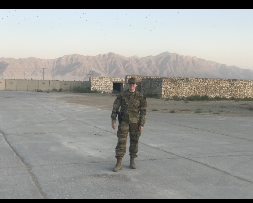 Eliza Rushlow in uniform smiling for a photo with mountains in the background.