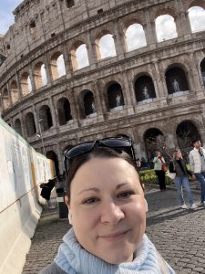 Amber Kirkpatrick taking a selfie with the coliseum behind her.