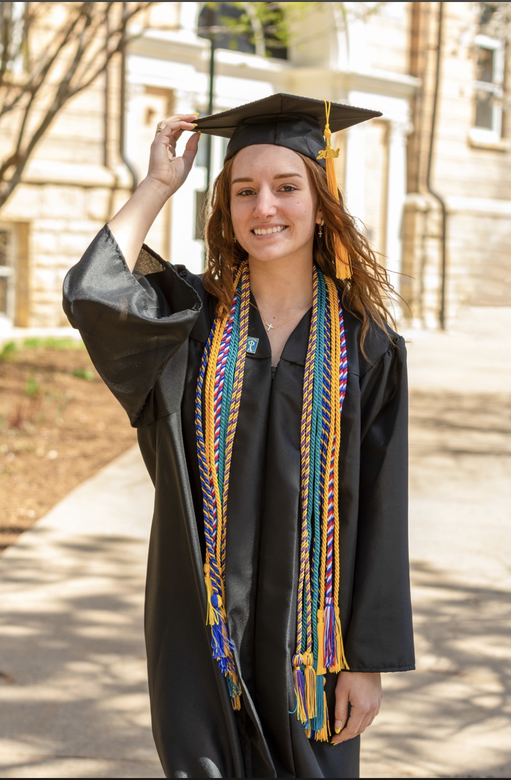 Ruthie Zahm in a graduation cap and gown smiling for a photo outside.