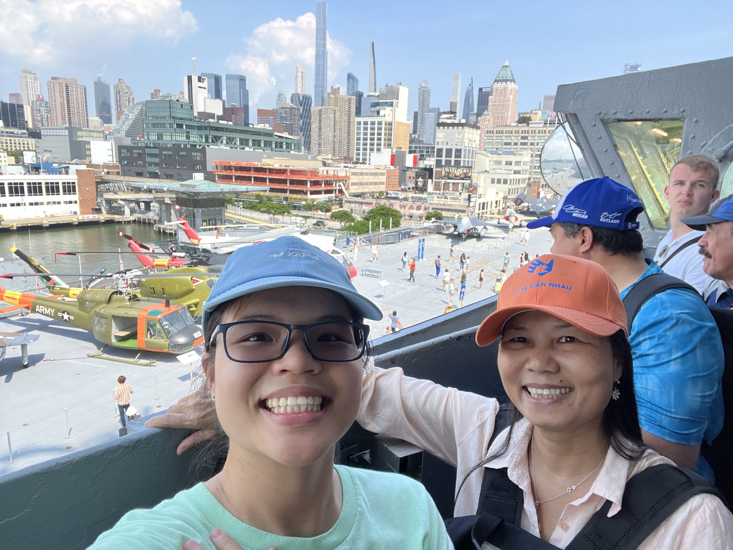 Thi Tran and a woman, both wearing baseball caps, overlooking a city.