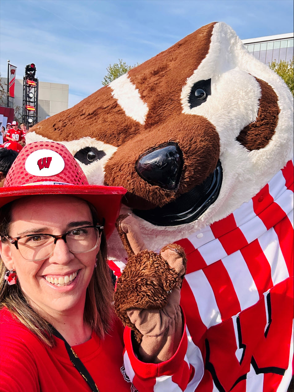 Elizabeth Parizo taking a picture with Bucky Badger wearing a red "Wisconsin" cowboy hat.