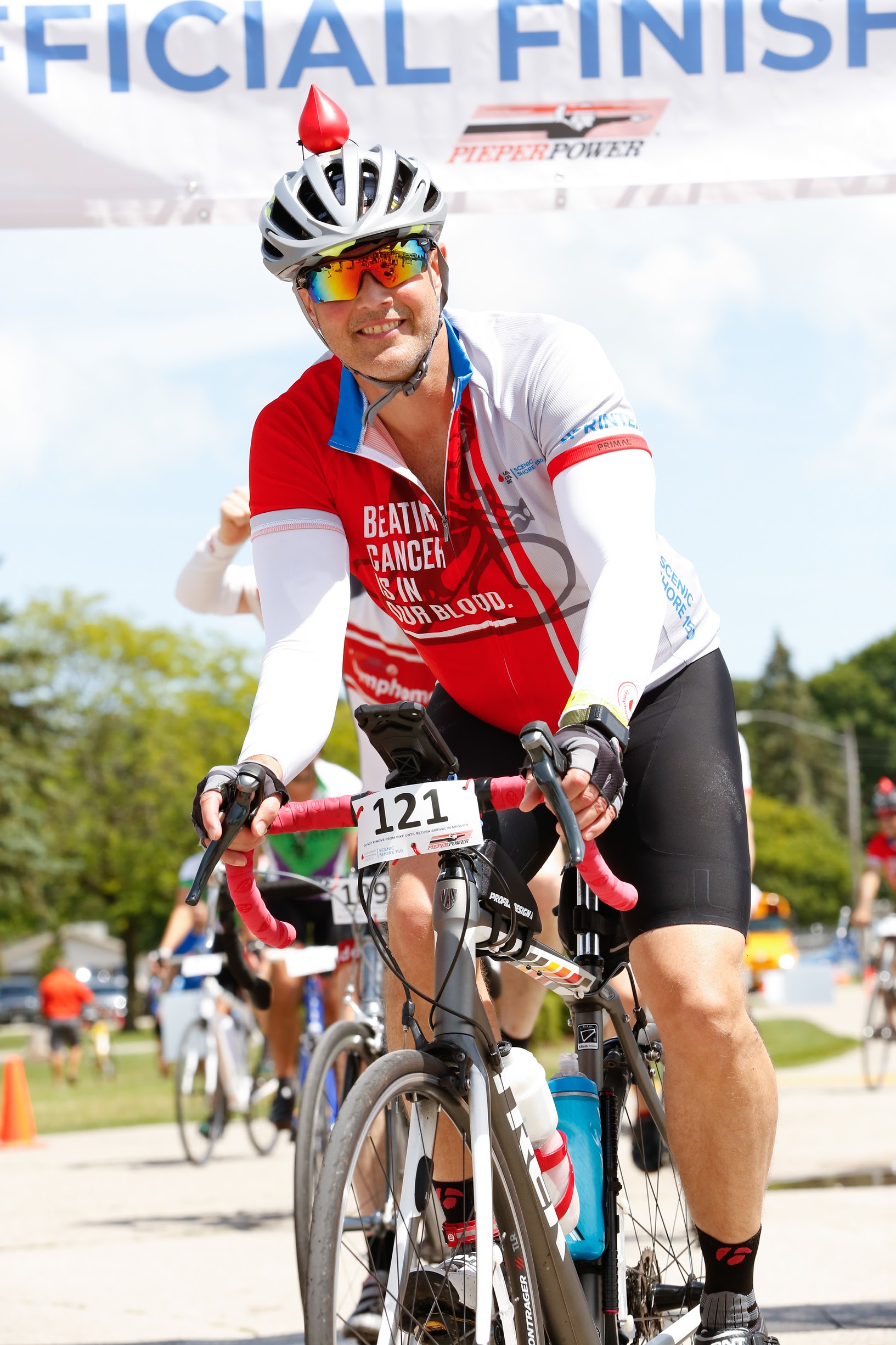 Pete Boll smiling for a photo while on a bike during a race as he gets to the finish line.