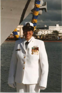 Lorainne Schwager in white uniform by a ship with a body of water in the background.