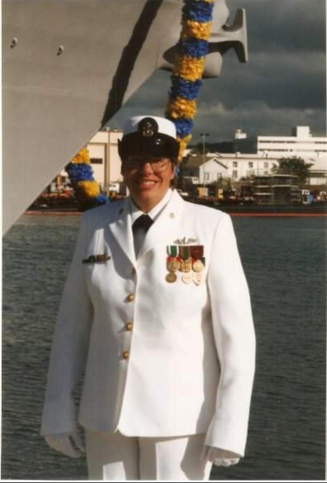 Lorainne Schwager in white uniform by a ship with a body of water in the background.