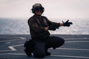 Frank Torres in uniform kneeling on a jet runway.