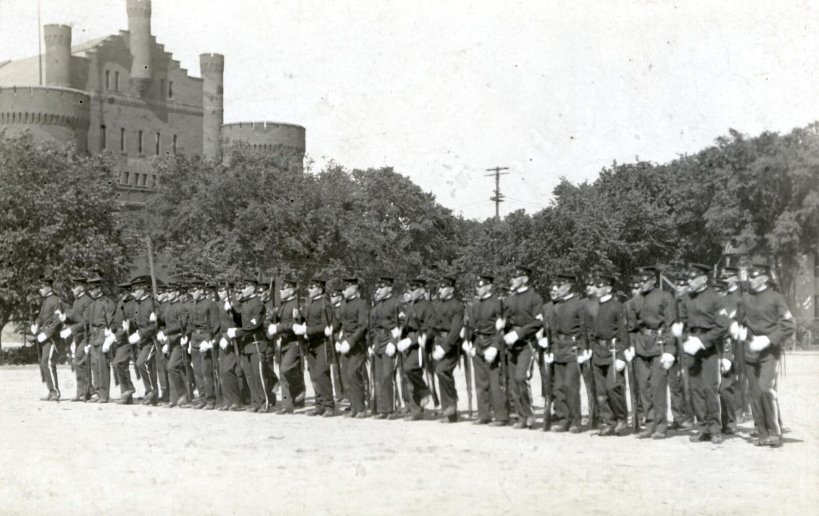A group of ROTC cadets stand in a line on Library Mall with the Red Gym in the background.