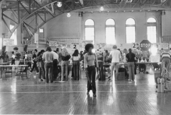 A woman walks away from a row of registration tables set up in the Red Gym.